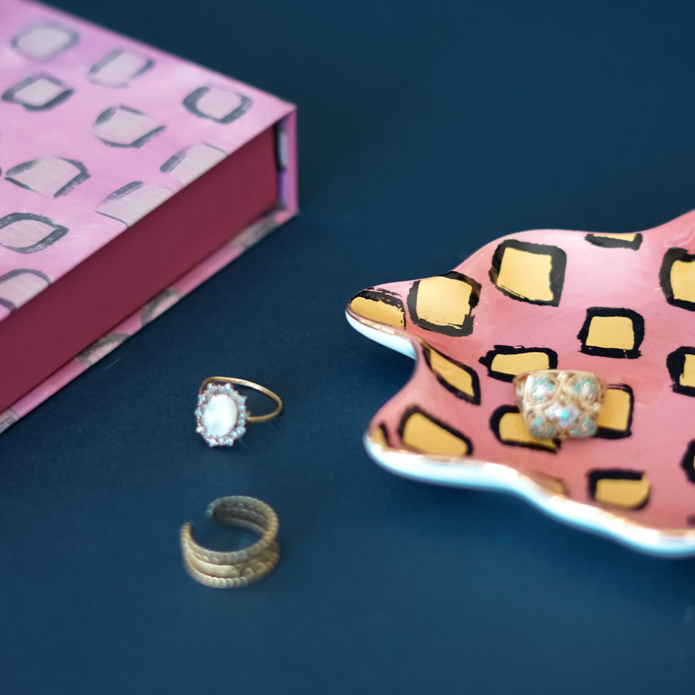 Pink jewelry box with rings on a blue surface